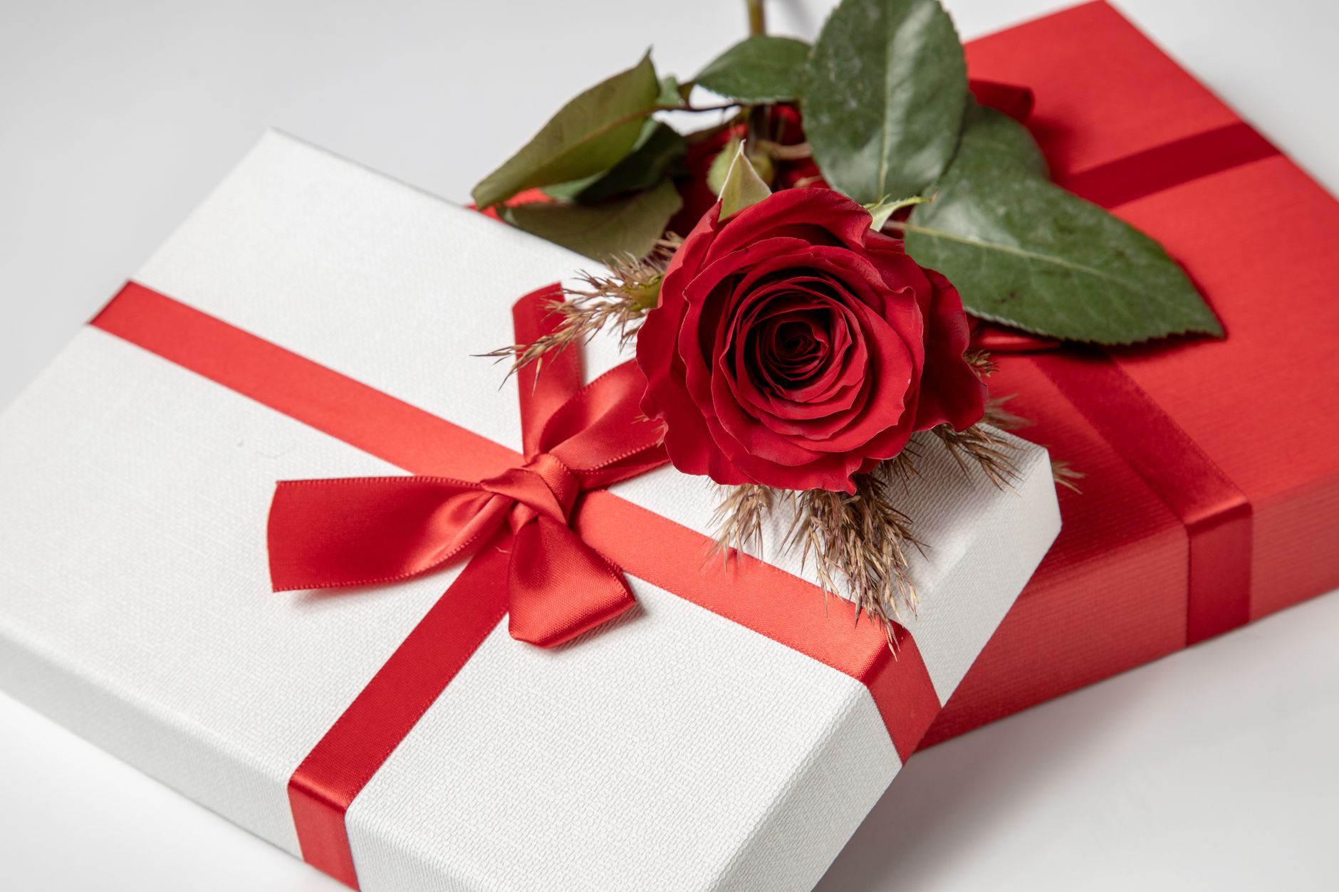 red rose on white and red gift boxes
